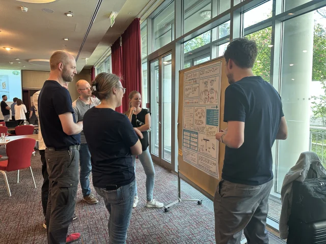 Mehrere Mitarbeitende stehen vor einem Methoden-Poster