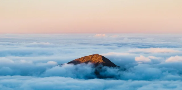 Ein Berggipfel, der aus den Wolken heraustritt