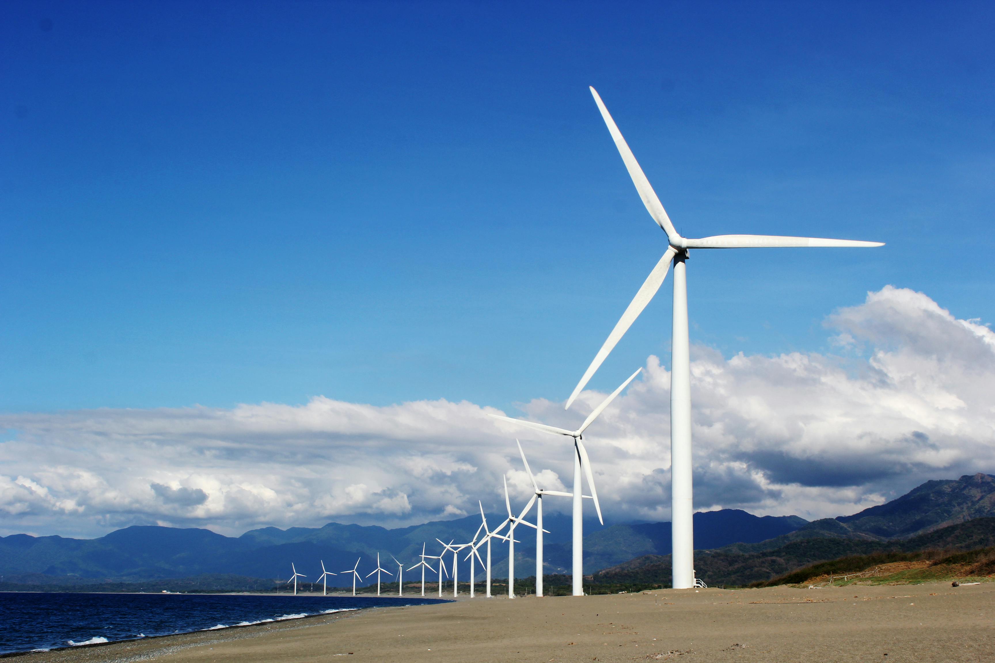 Eine Reihe Windräder vor blauem Himmel und Bergen
