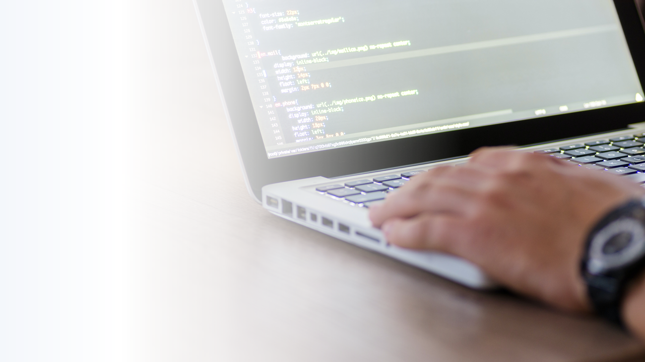 Hand auf Laptop mit Programmiercode